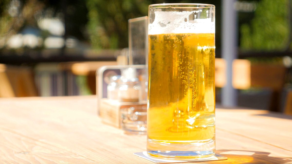 木のテーブルに置かれた、よく冷えた生ビールのジョッキのイメージ写真