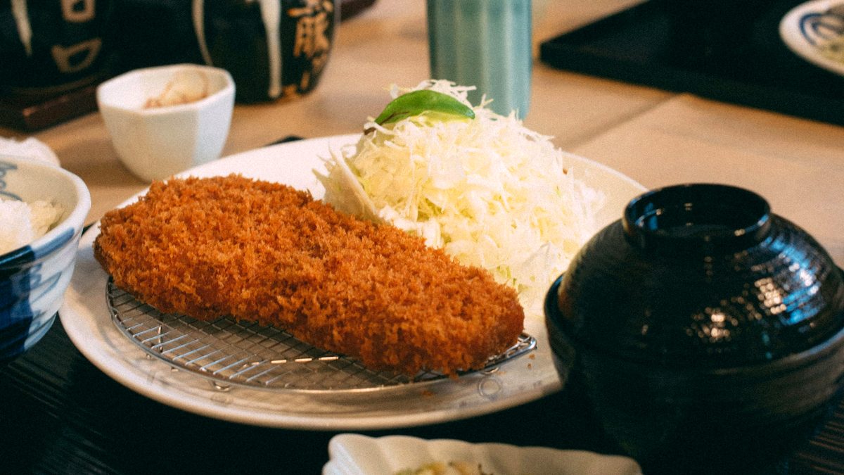とんかつ定食のイメージ写真。揚げたてのロースカツと千切りキャベツ、味噌汁が並んだお盆
